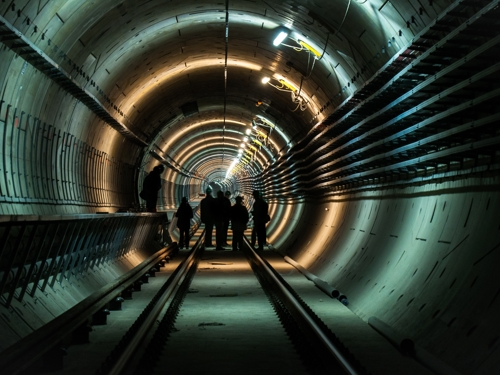 Silueta skupiny ľudí v osvetlenom rozostavanom železničnom tuneli