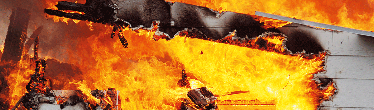 A wooden building engulfed in fire during a fire resistance test