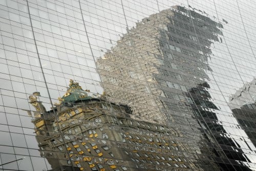 A distorted reflection coming from two opposite buildings on a glass facade of another building