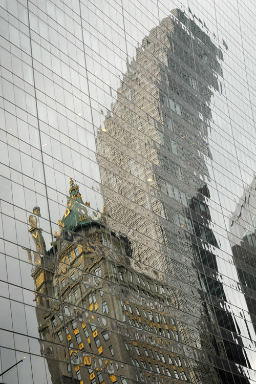 A distorted reflection coming from two opposite buildings on a glass facade of another building