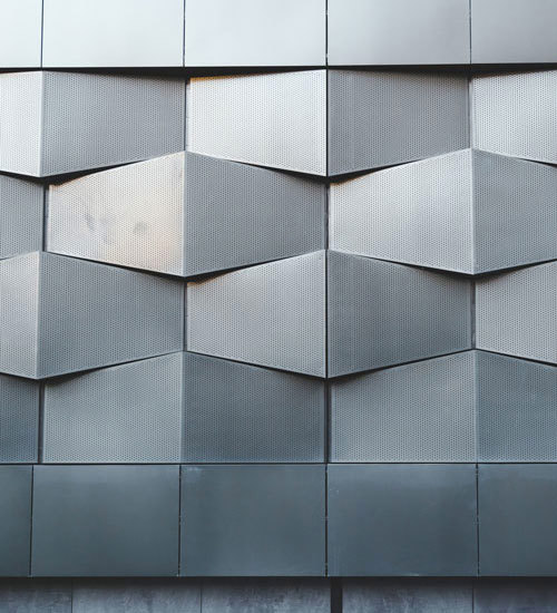 Slika nove stavbe s pročeljem iz abstraktnega črnega kovinskega arhitekturnega vzorca. 