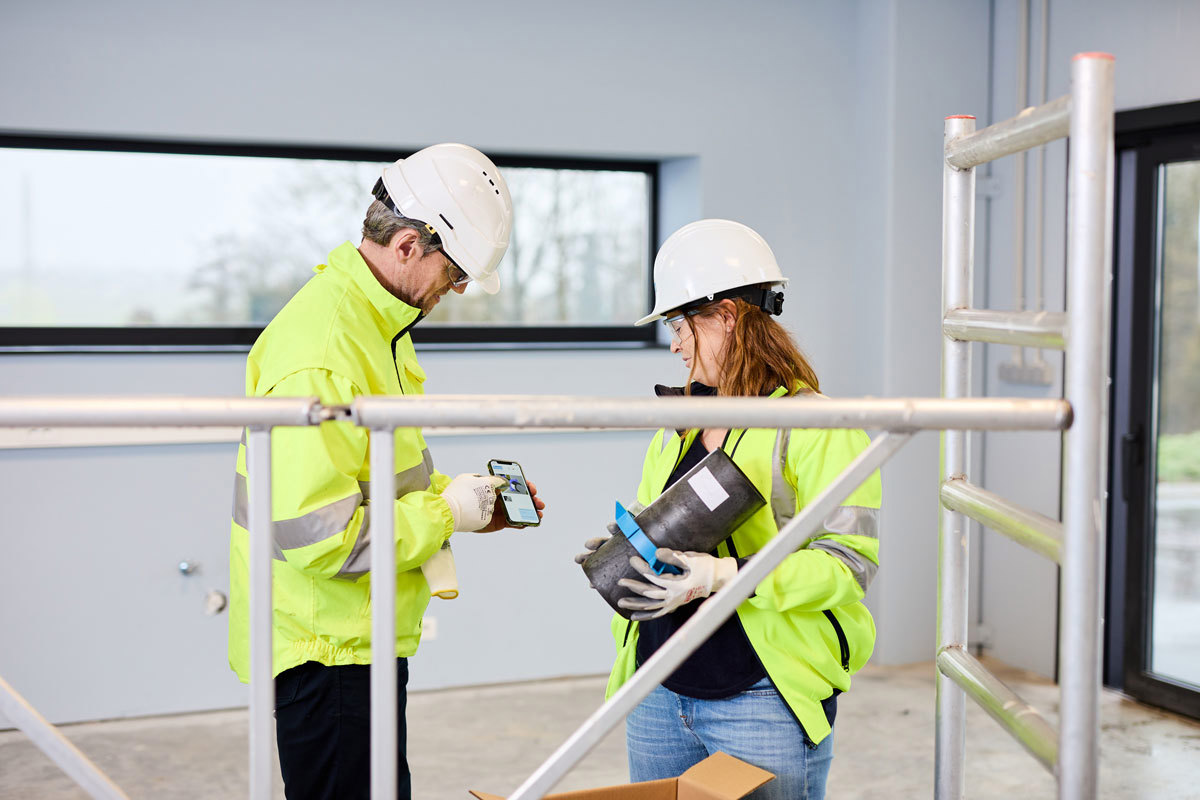 Man on the left is showing the woman on the right the mobile version of Promat’s firestopping Selector® App.