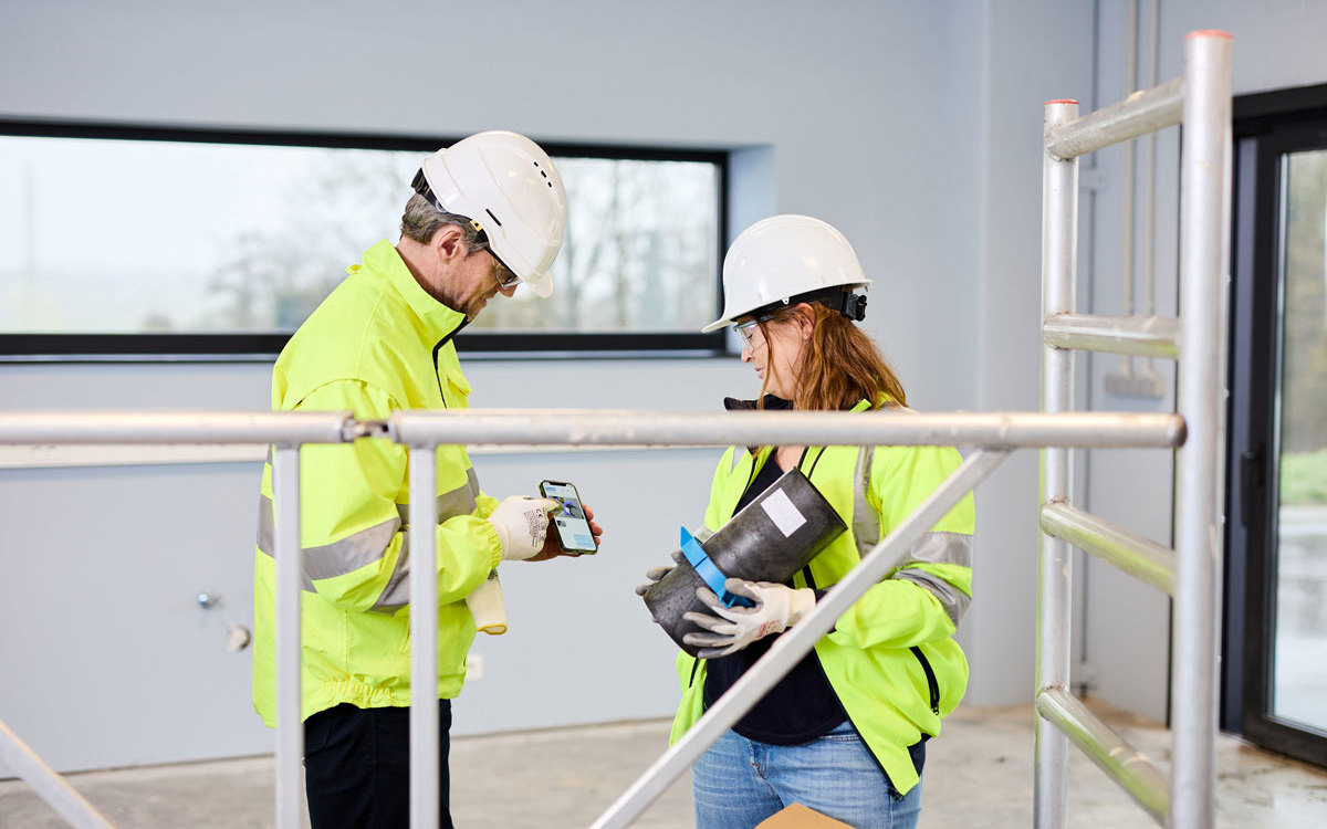 Man on the left is showing the woman on the right the mobile version of Promat’s firestopping Selector® App.