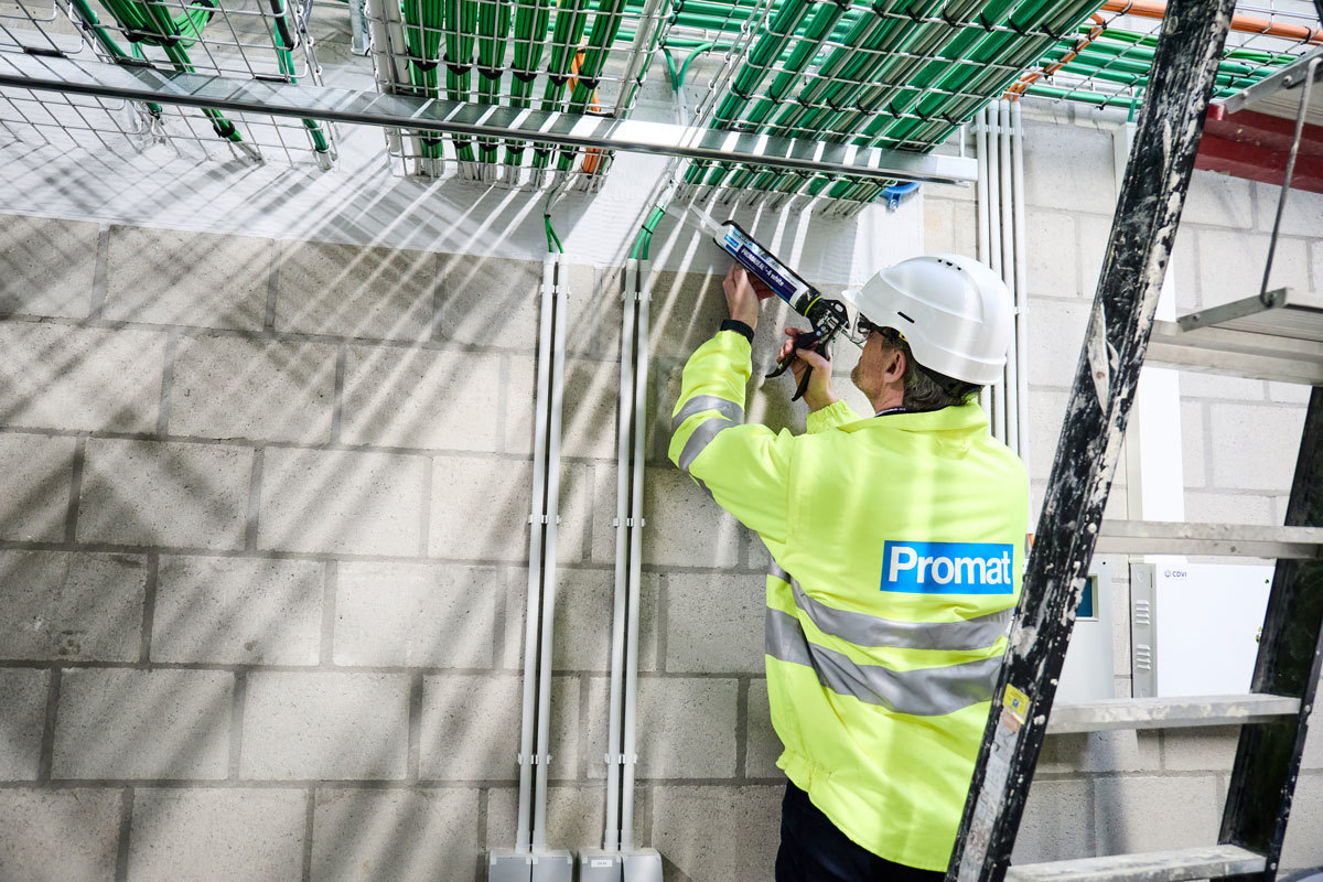 A man working the space between the penetrating material and the inside edge of the penetration opening.