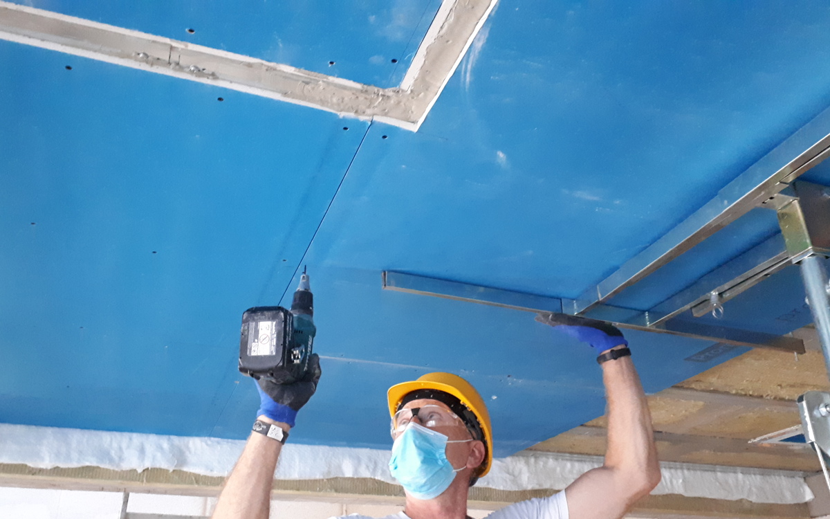 Mężczyzna instalujący zabezpieczenie ogniochronne w postaci płyty Promatect-100X