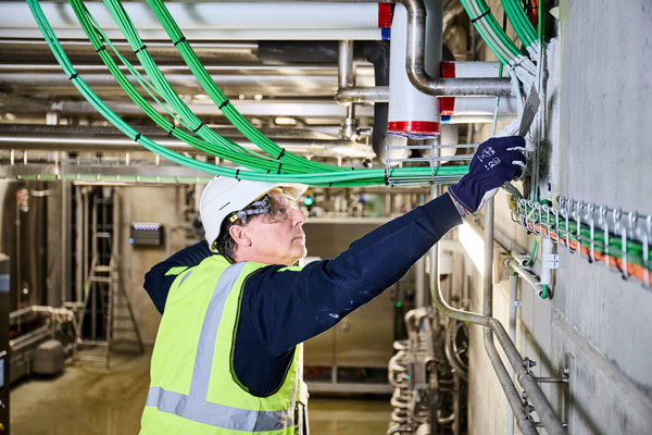An installer sealing the service penetration opening with fire stopping coating PROMASTOP®-CC