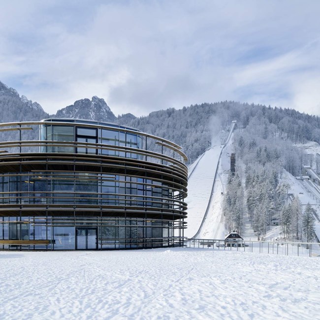clădirea centrală a Planica Nordic Center cu vedere de la dealurile de sărituri cu schiurile