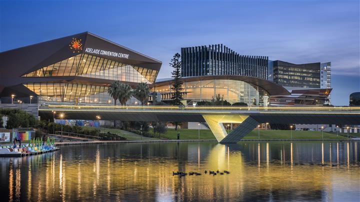 Adelaide Convention Center a priľahlé budovy za mostom a jazerom s odrazmi svetla