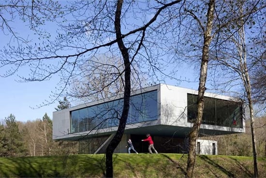Dve deti sa naháňajú pred Maison Sidobre. V popredí siluety troch stromov