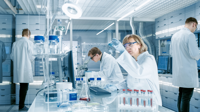 Naučnici u zaštitnim naočarama rade u naučnoj laboratoriji uz pomoć instrumenata i pribora poput epruveta i hemikalija.