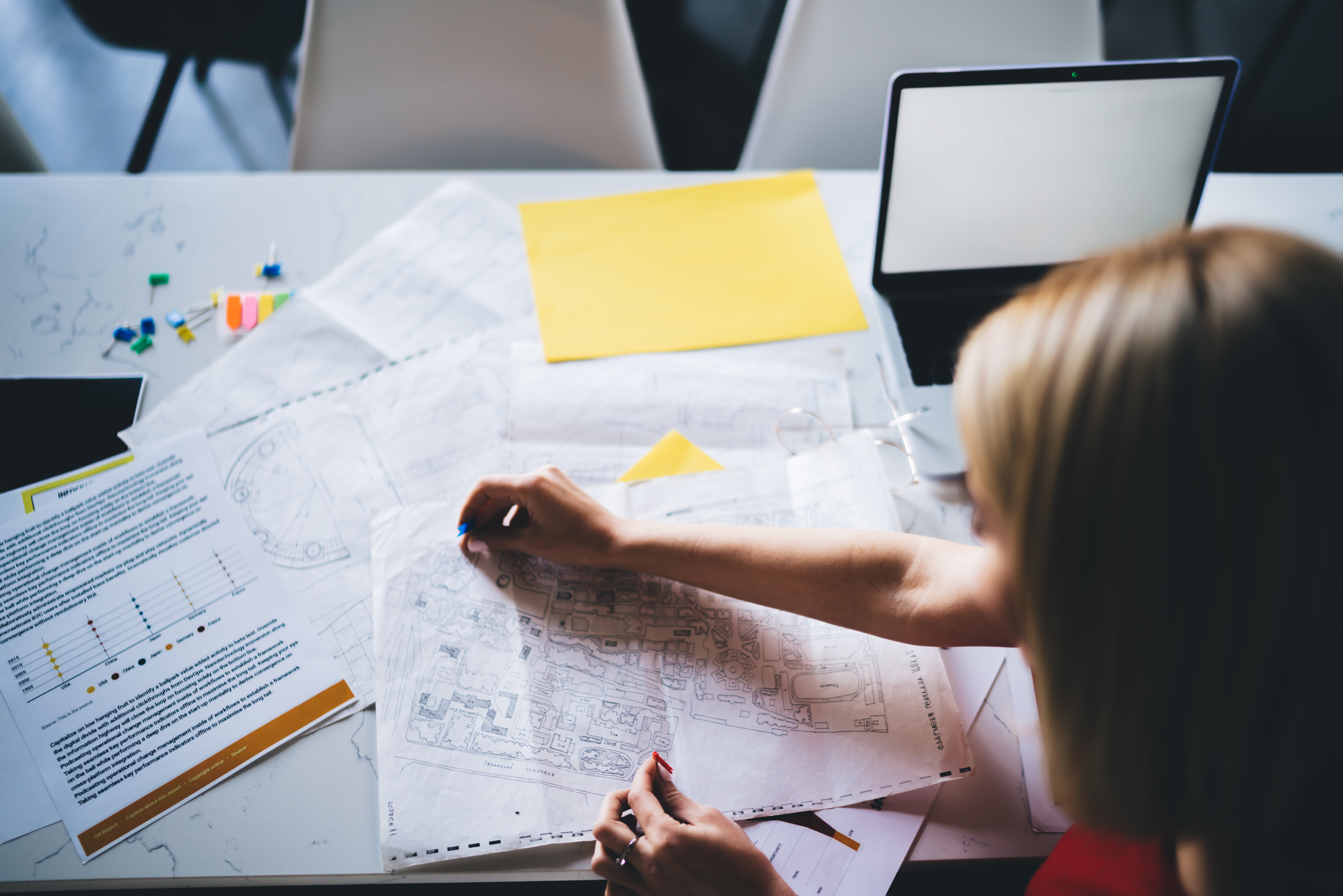 Projektant na radnom mestu planira i analizira projekat na stolu na kome se nalaze dokumenti, podsetnici i tablet računar.