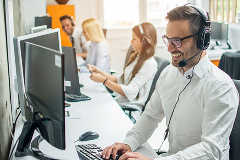 Call centar u kome nasmejani i uredni agenti u belim košuljama i sa slušalicama sa mikrofonom pružaju uslugu tehničke podrške