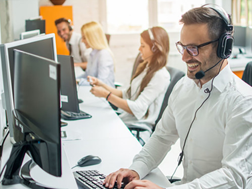 Call centar u kome nasmejani i uredni agenti u belim košuljama i sa slušalicama sa mikrofonom pružaju uslugu tehničke podrške