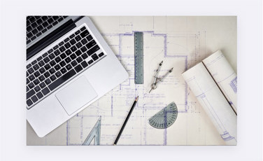 Laptop, projekt na papieri a geometrické pomôcky
