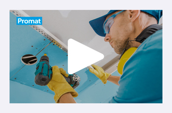 Slika zaslonskega zajema videa, v katerem delavec v modri majici, z zaščitnimi očali in rumenimi rokavicami, na strop vgrajuje modro obarvano požarno ploščo. 
