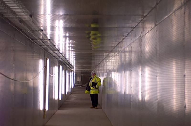 Inženir v rumeni odbojni jakni stoji v tunelu požarnega sektorja. 