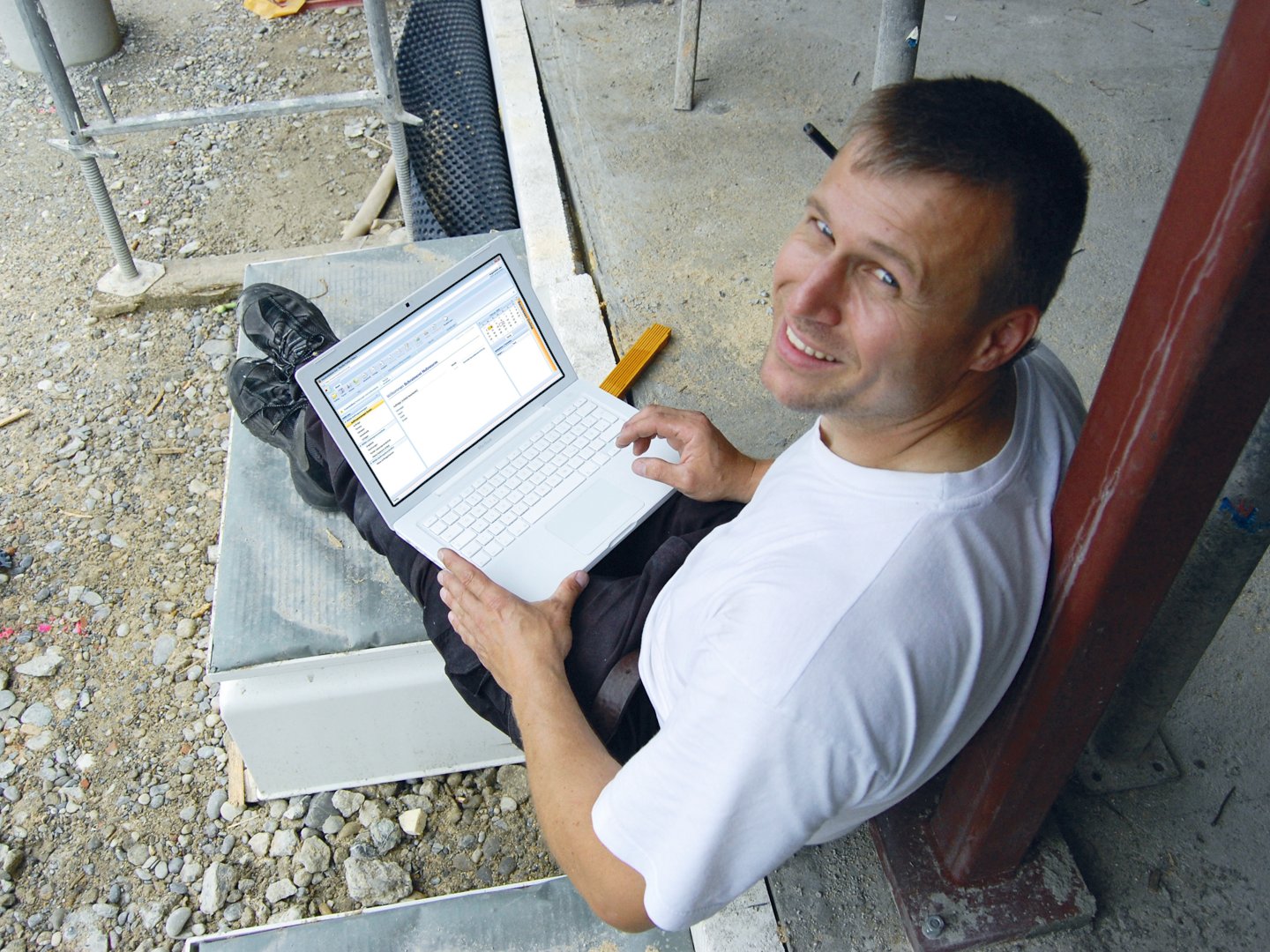 Usmievajúci sa projektant na stavbe pracuje s BIM na laptope