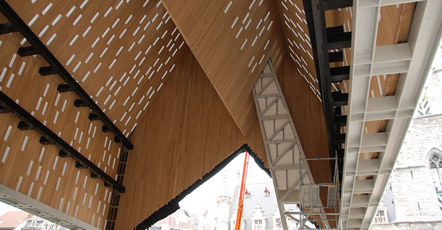 Slika notranje strani strehe, narejene iz lesenih elementov in belo črne konstrukcije. 