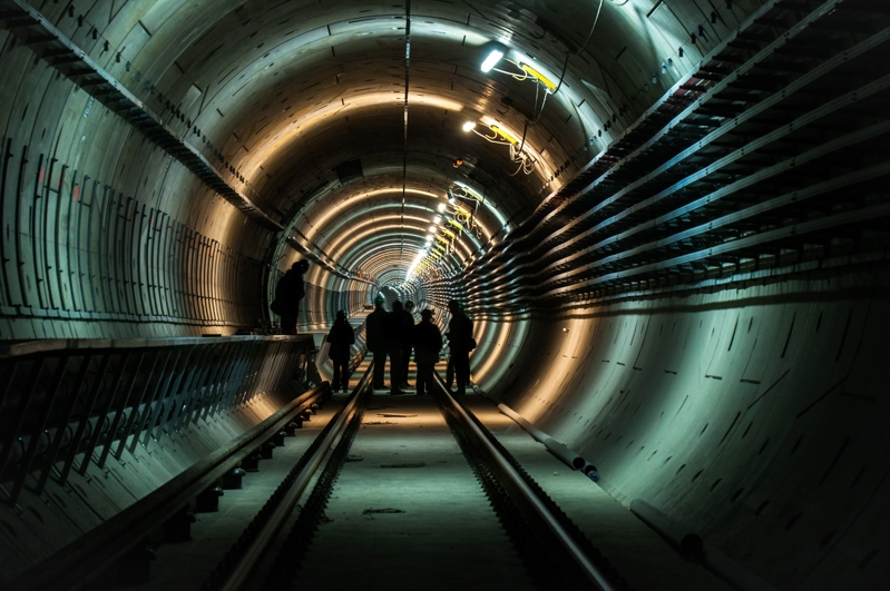 Na slici je skupina inženjera koji provjeravaju instalacije u nedovršenom tunelu.